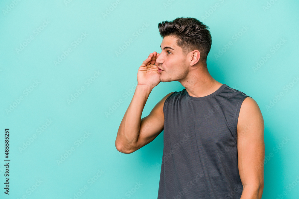 Young caucasian man isolated on blue background is saying a secret hot braking news and looking aside Young caucasian man isolated on blue background is saying a secret hot braking news and looking aside