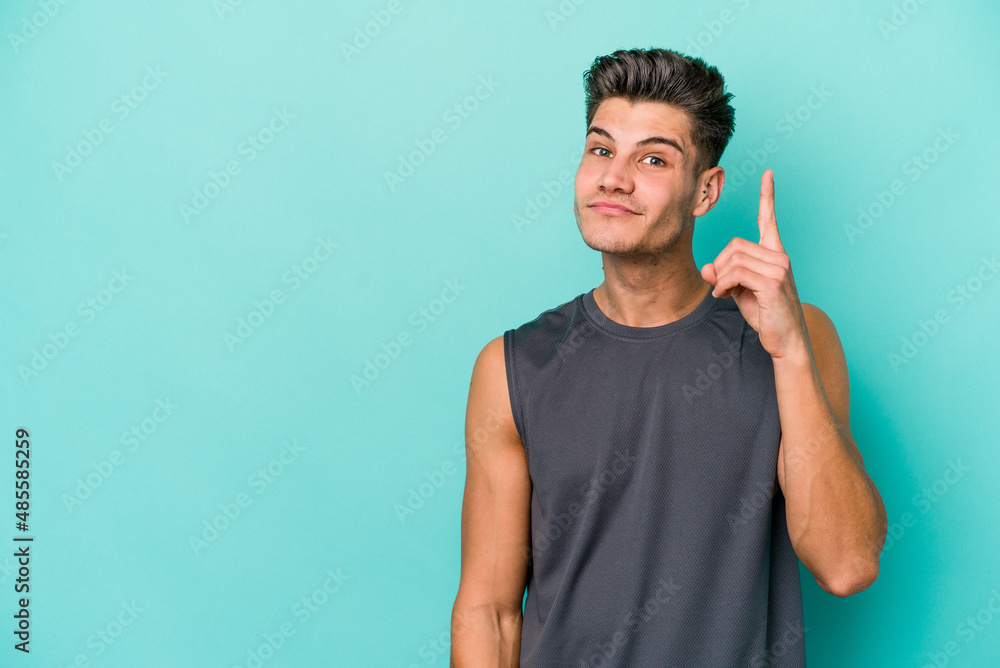 Young caucasian man isolated on blue background showing number one with finger. Young caucasian man isolated on blue background showing number one with finger.