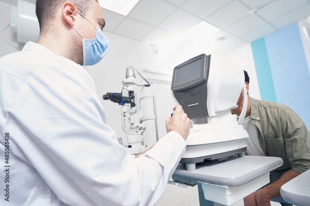 Professional doctor working at the refraction machine