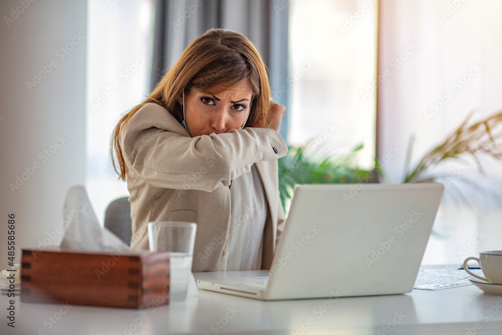 Business woman solves business obligations, self-employed woman sits at a desk in the office and works on a laptop, less productive due to illness, runny nose is unhealthy Business woman solves business obligations, self-employed woman sits at a desk in the office and works on a laptop, less productive due to illness, runny nose is unhealthy