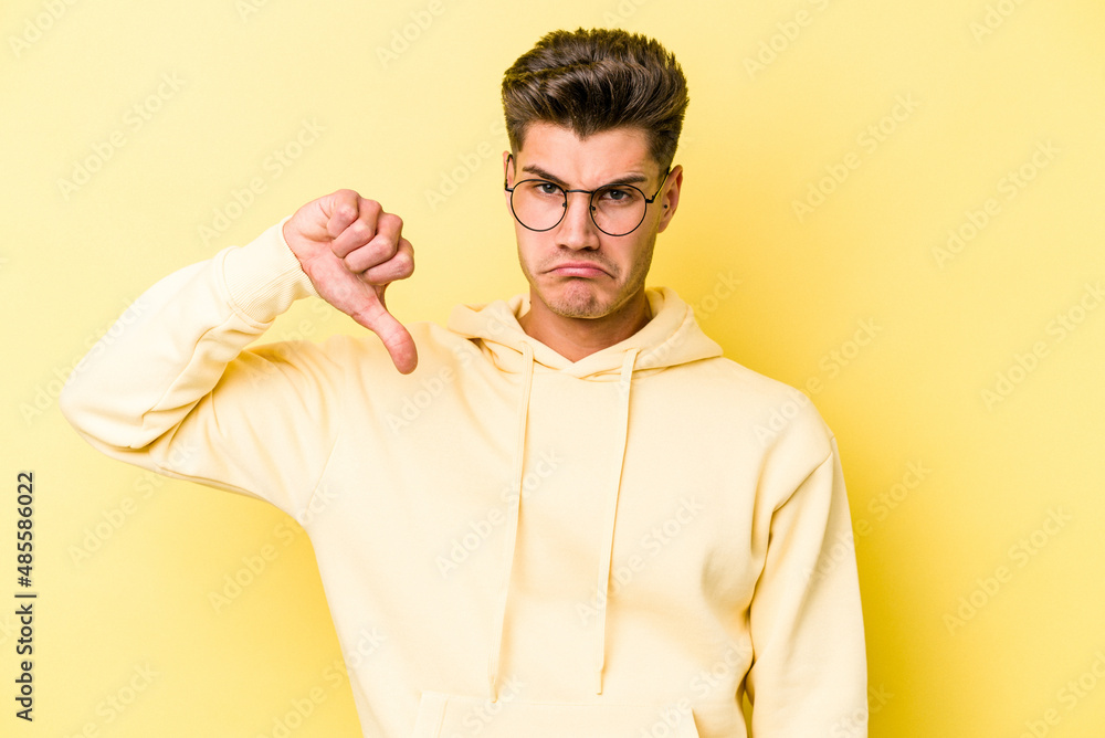 Young caucasian man isolated on yellow background showing a dislike gesture, thumbs down. Disagreement concept. Young caucasian man isolated on yellow background showing a dislike gesture, thumbs down. Disagreement concept.