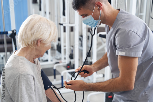 Doctor using blood pressure gauge on aging woman arm