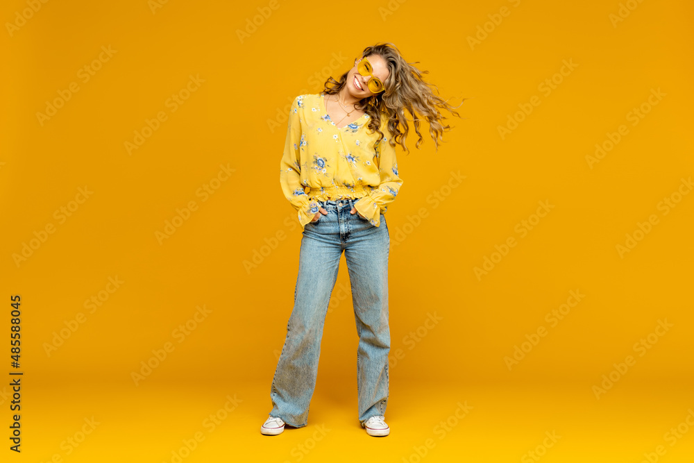 Fototapeta premium stylish happy smiling blond woman posing in jeans on yellow background