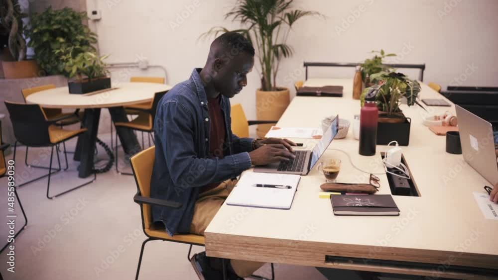 Black man taking notes and working on a laptop Black man taking notes and working on a laptop