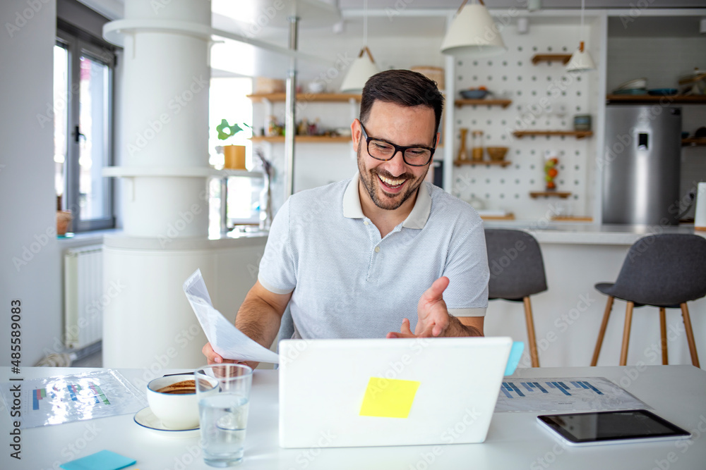 A young serious professional businessman, a focused student who wears glasses works on a laptop, learns at a distance using a computer and looks at the screen A young serious professional businessman, a focused student who wears glasses works on a laptop, learns at a distance using a computer and looks at the screen