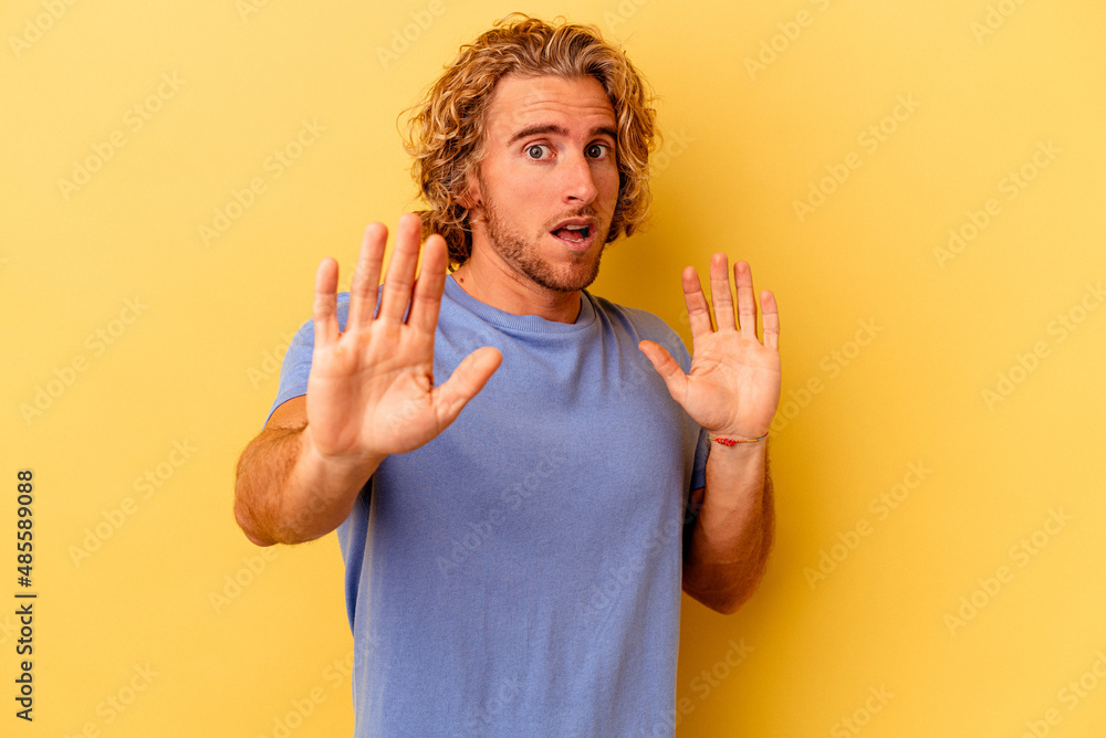 Young caucasian man isolated on yellow background being shocked due to an imminent danger Young caucasian man isolated on yellow background being shocked due to an imminent danger