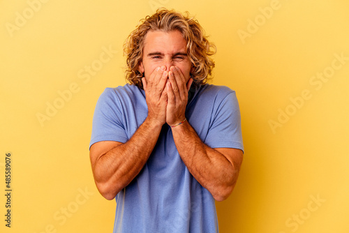 Young caucasian man isolated on yellow background laughing about something  covering mouth with hands.