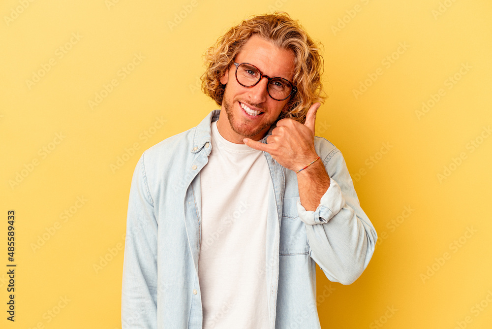 Young caucasian man isolated on yellow background showing a mobile phone call gesture with fingers. Young caucasian man isolated on yellow background showing a mobile phone call gesture with fingers.