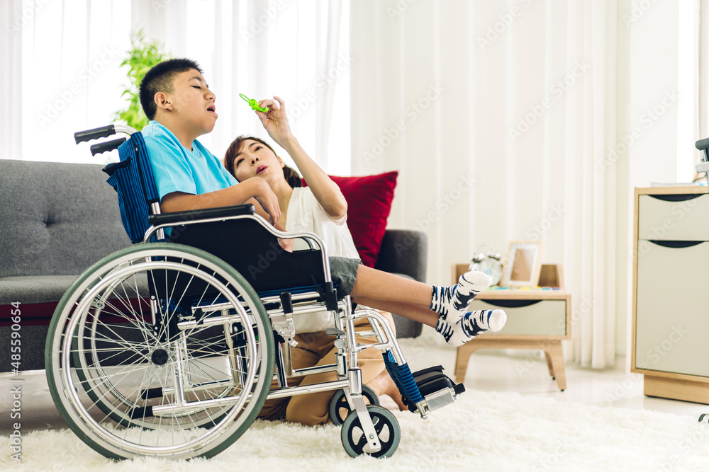 Portrait of asian physiotherapist carer helping and playing with special disabled child health problem by doing exercises sitting in wheelchair in rehabilitation clinic.disability care concept Portrait of asian physiotherapist carer helping and playing with special disabled child health problem by doing exercises sitting in wheelchair in rehabilitation clinic.disability care concept