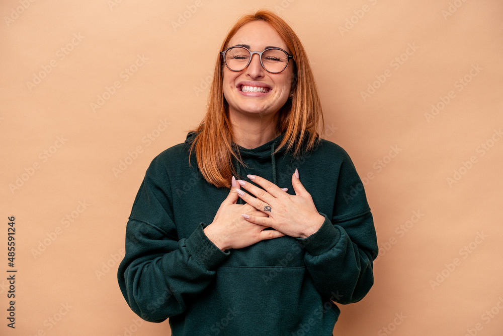 Young caucasian woman isolated on beige background laughing keeping hands on heart, concept of happiness. Young caucasian woman isolated on beige background laughing keeping hands on heart, concept of happiness.