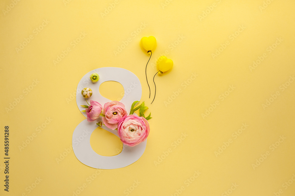 Greeting Card International Women's Day on March 8th. Pink ranunculus decorates the number eight and yellow balloons on paper background. Soft focus. Top view. Copy Space.