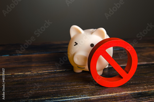 Piggy bank and prohibition sign NO. Bypass restrictions, loopholes in laws. Lifting of sanctions, unblocking and unfreezing of assets. Money laundering and legalization of capital. Cancel restrictions photo