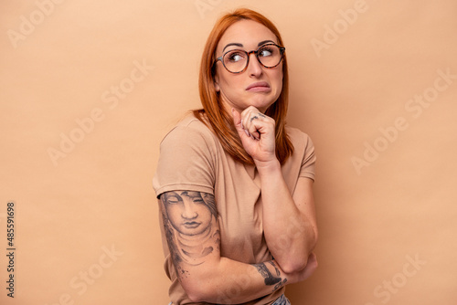 Young caucasian woman isolated on beige background confused  feels doubtful and unsure.