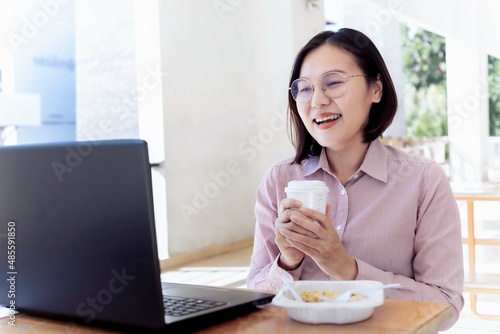 working women Sit with a cup of coffee on the lunch table and show a bright smile. and staring at the laptop computer photo