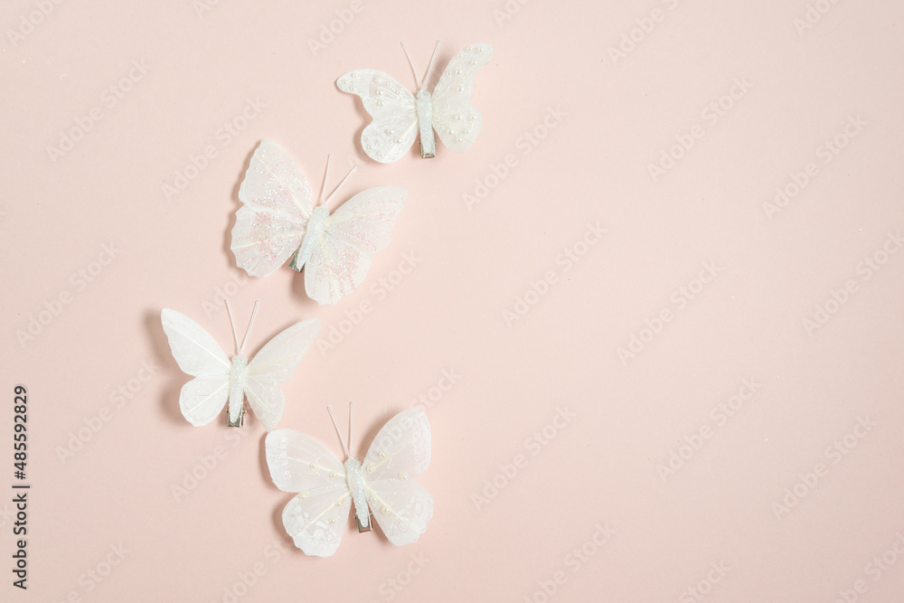 handmade white butterflies on a pale pink background, free space for text, elegant spring composition