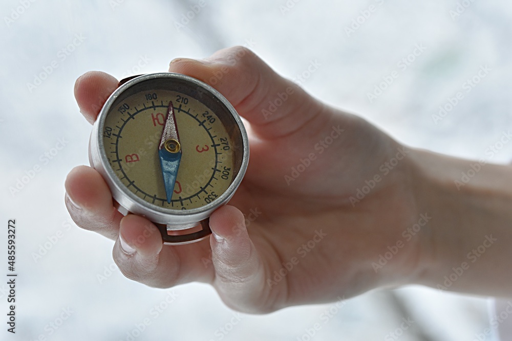 hand holding a compass on the background of a contour map hand holding a compass on the background of a contour map