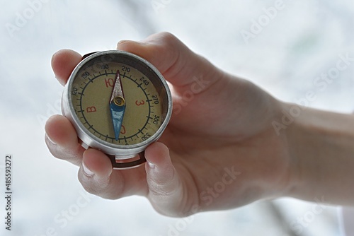 hand holding a compass on the background of a contour map