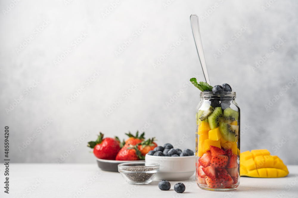 Rainbow salad of fresh fruits and berries in tall glass jar. Strawberry, mango, kiwi, blueberry pieces Rainbow salad of fresh fruits and berries in tall glass jar. Strawberry, mango, kiwi, blueberry pieces