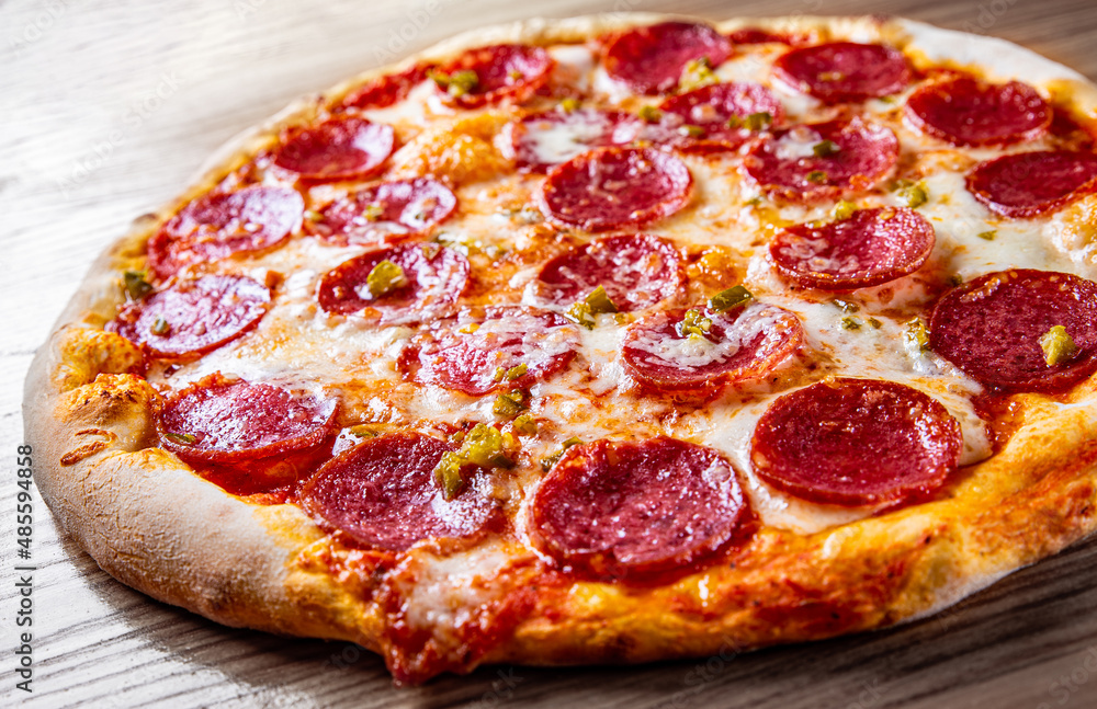 Hot Pepperoni Pizza with Mozzarella cheese, salami, Tomato sauce, pepper, Spices. Italian pizza on wooden background Hot Pepperoni Pizza with Mozzarella cheese, salami, Tomato sauce, pepper, Spices. Italian pizza on wooden background