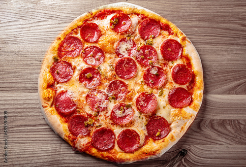 Hot Pepperoni Pizza with Mozzarella cheese, salami, Tomato sauce, pepper, Spices. Italian pizza on wooden background