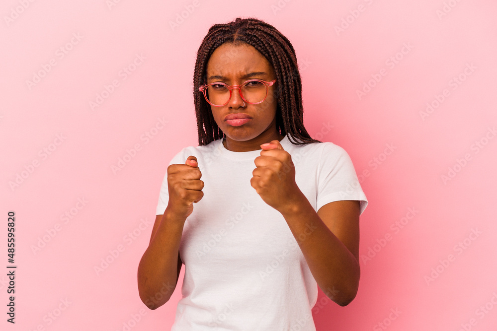 Young african american woman isolated on pink background showing fist to camera, aggressive facial expression. Young african american woman isolated on pink background showing fist to camera, aggressive facial expression.
