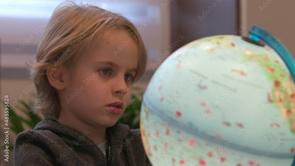 Happy male child playing and looking at globe with world animals and continents. Curious little boy using toy for learning and leisure. Kid and education at home Happy male child playing and looking at globe with world animals and continents. Curious little boy using toy for learning and leisure. Kid and education at home