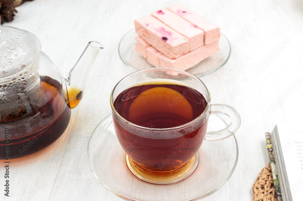 teapot and cup of black tea on a wooden table and pink fruit marshmallow teapot and cup of black tea on a wooden table and pink fruit marshmallow