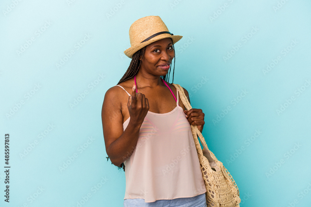 Young african american woman wearing summer clothes isolated on blue background pointing with finger at you as if inviting come closer. Young african american woman wearing summer clothes isolated on blue background pointing with finger at you as if inviting come closer.