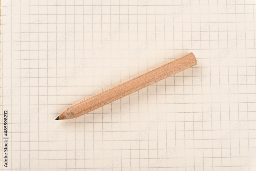 A pencil lies on a piece of squared paper. A pencil lies on a piece of squared paper.