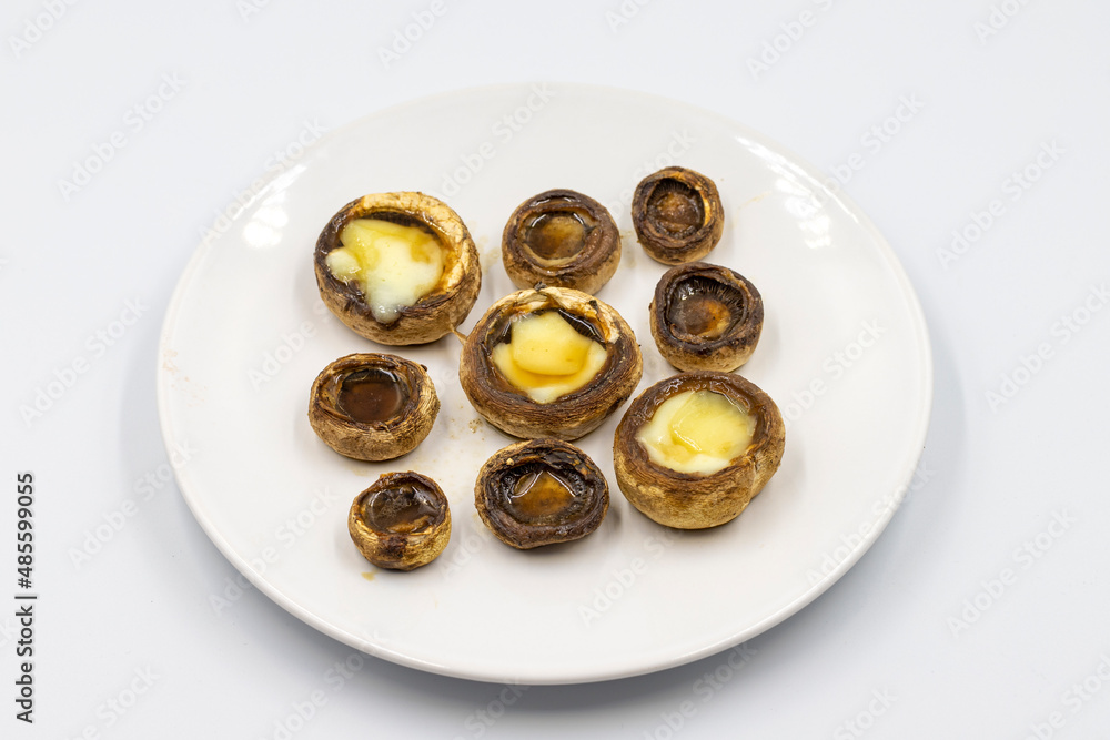 Baked mushrooms in a ceramic plate on a white background. Cultivated mushroom or portabello mushroom Baked mushrooms in a ceramic plate on a white background. Cultivated mushroom or portabello mushroom
