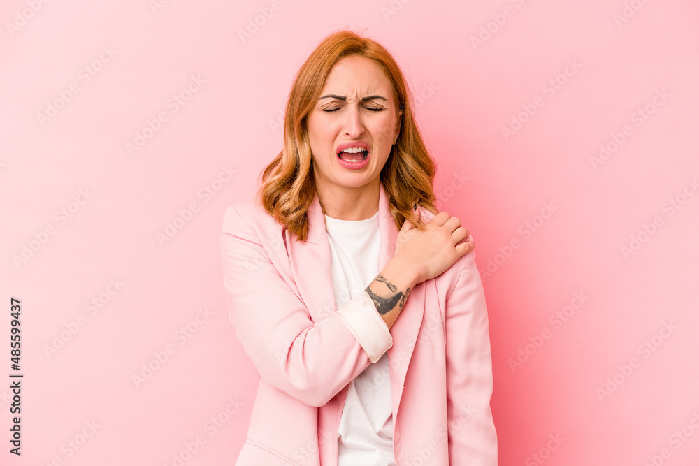 Young caucasian woman isolated on pink background having a shoulder pain. Young caucasian woman isolated on pink background having a shoulder pain.