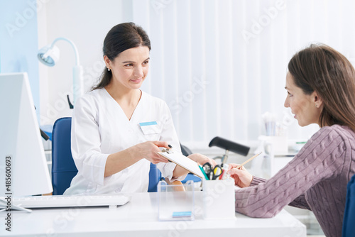 Female patient affixing her signature to document in doctor office