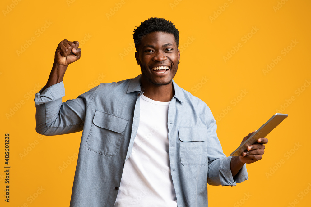 Happy african american guy sharing success, using pad Happy african american guy sharing success, using pad