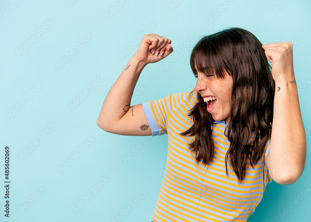Fototapeta premium Young Argentinian woman isolated on blue background raising fist after a victory, winner concept.