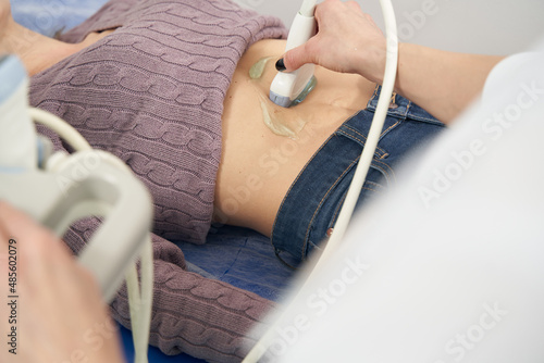 Experienced sonographer performing abdominal ultrasonography on woman photo