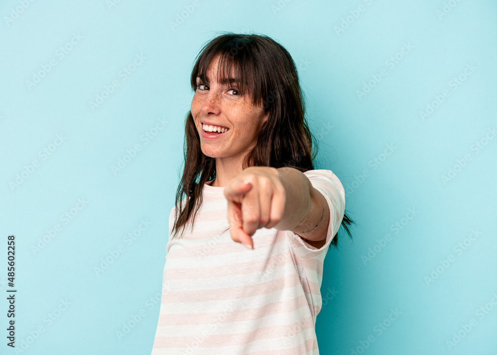 Fototapeta premium Young Argentinian woman isolated on blue background cheerful smiles pointing to front.