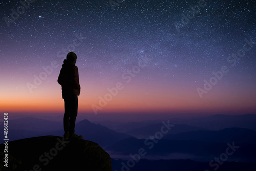 Young traveler and backpacker watched the star and milky way alone on top of the mountain. He enjoyed traveling and was successful when he reached the summit.