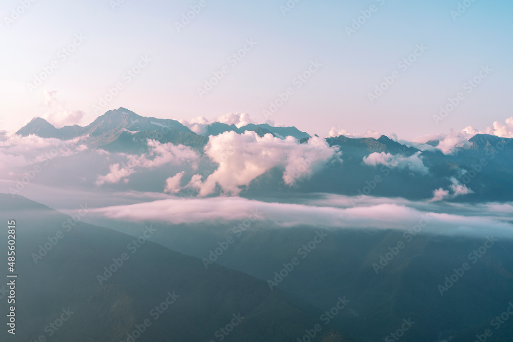 beautiful view of the mountains of the Caucasus range in white clouds at sunset, natural background landscape blue sky