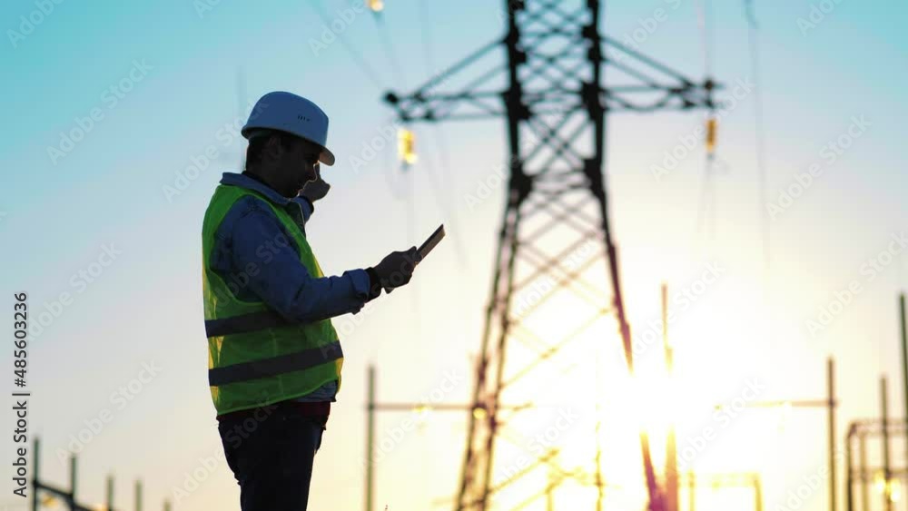 Industry energy business concept. Silhouette electrical engineer a working near tower with electricity at sunset time. Electrical worker inspect voltage electricity pylon. Power generation industry. Industry energy business concept. Silhouette electrical engineer a working near tower with electricity at sunset time. Electrical worker inspect voltage electricity pylon. Power generation industry.