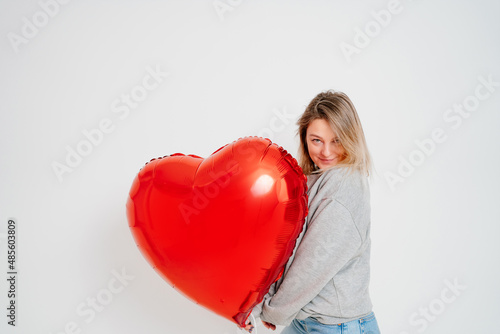 an blonde woman with a large red heart-shaped balloon on a white background.  © andrey