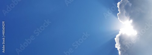 Holy spirit long banner. Blue sky with the rays of the sun coming out of a white cloud. Religious background with sky and sunbeams. Sunny clear weather background for weather forecast and meteorology.