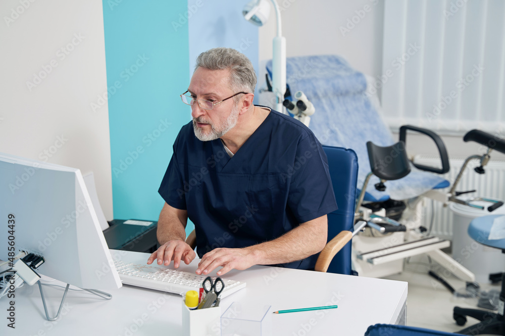 Physician working on desktop computer in his office Physician working on desktop computer in his office