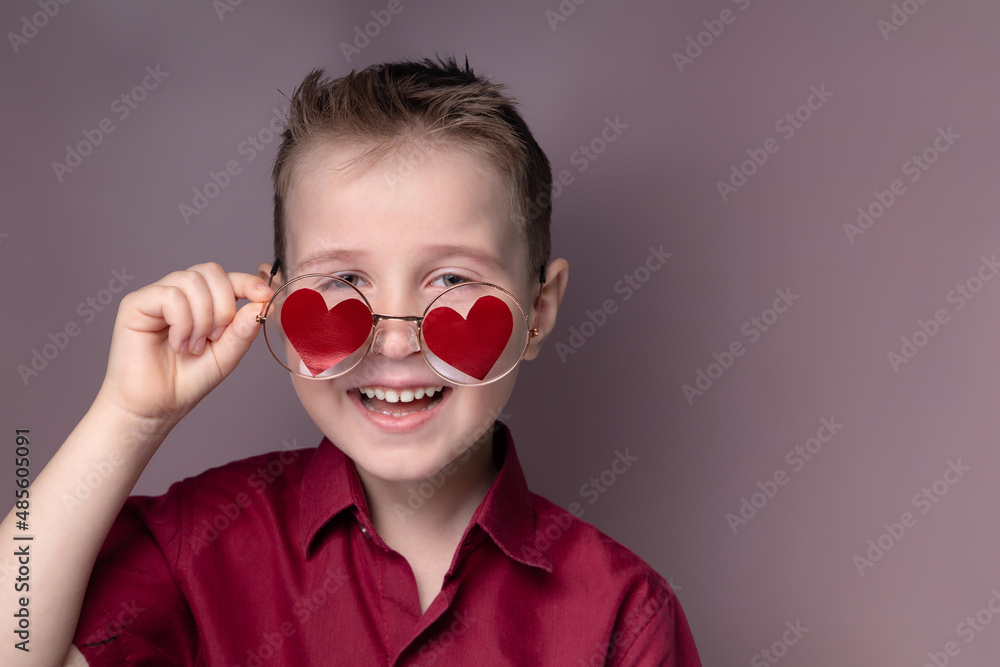 Smiling little boy in glasses with red hearts and a burgundy shirt Smiling little boy in glasses with red hearts and a burgundy shirt