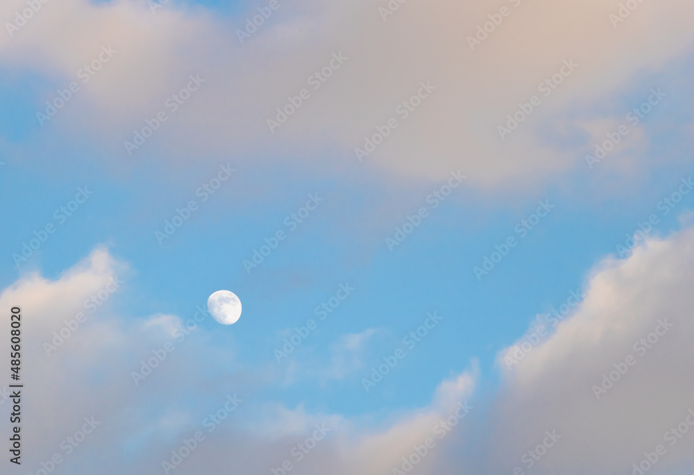 Beautiful shot of white clouds and a small moon on the sky