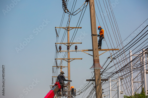 The male worker crane cable car repairs the electric pole and growing