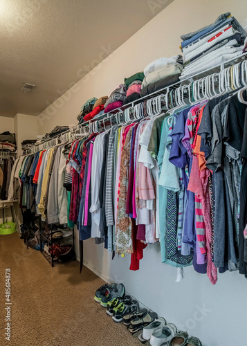 Vertical Walk in closet with organized hanging and stacked clothes and shoes