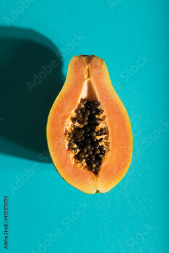 Ripe cut papaya on blue pastel background. Top view, close up, hard light.