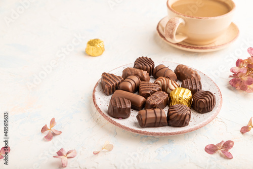 Chocolate candies with cup of coffee. side view, close up.