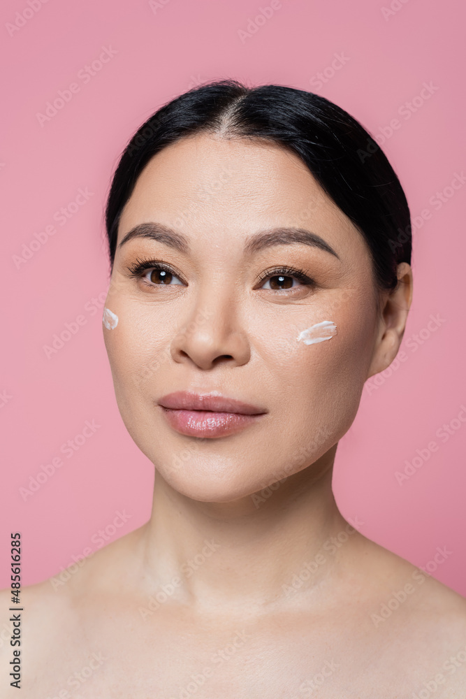 Asian woman with naked shoulders and cream on face isolated on pink Asian woman with naked shoulders and cream on face isolated on pink