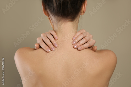 Back view of woman with perfect smooth skin on beige background, closeup. Beauty and body care